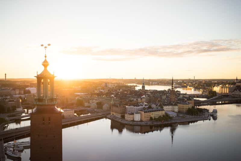 Sunrise over City Hall and the Old Town Aerial view of Stockholm City Hall tower backlit by the sun, with the Old Town and surrounding water glowing in soft morning light.